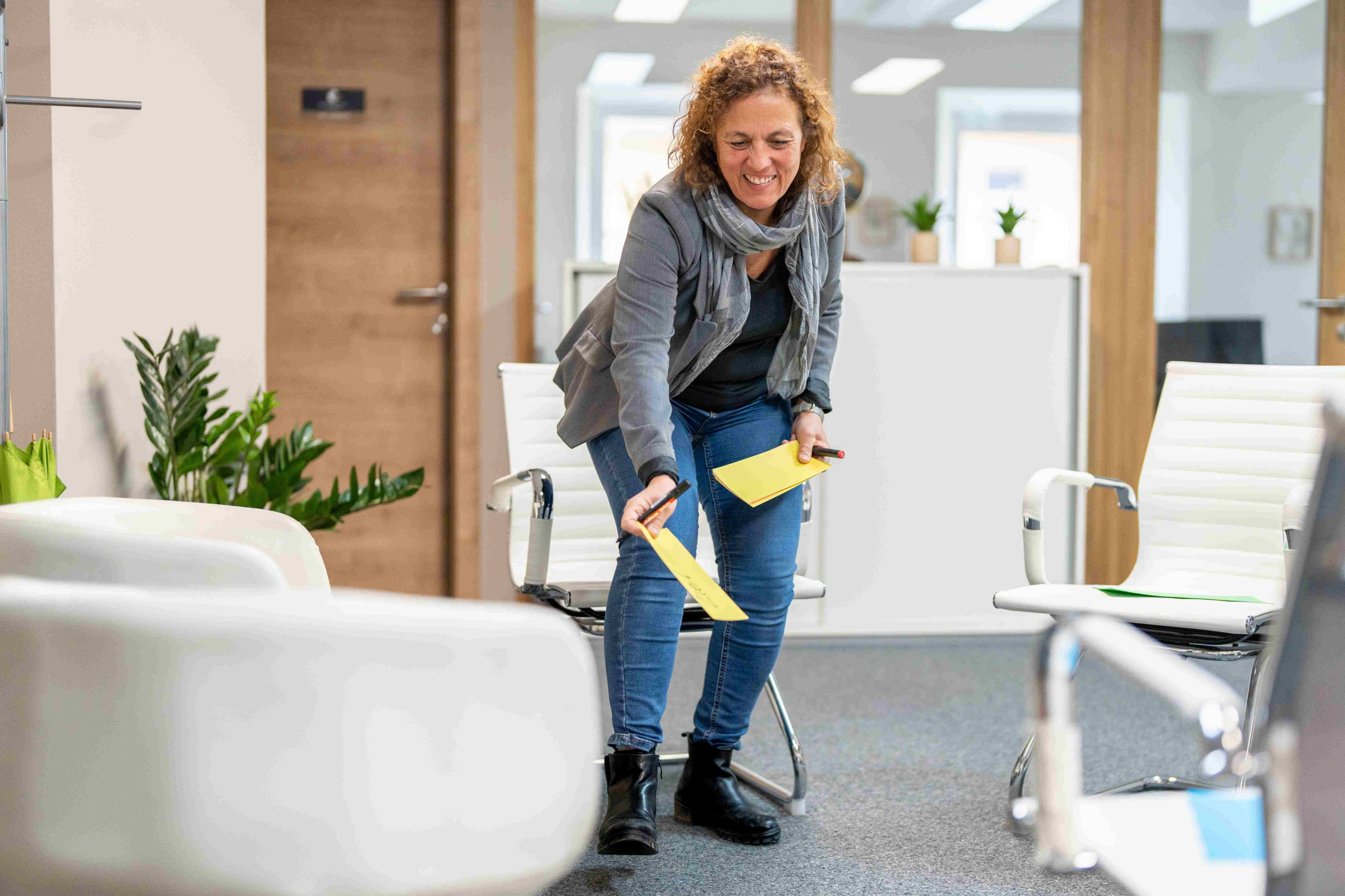 Birgit Seymann in ihrem Büro beim Auflegen von Moderationskarten am Boden zum Sichtbarmachen von Arbeitsschritten
