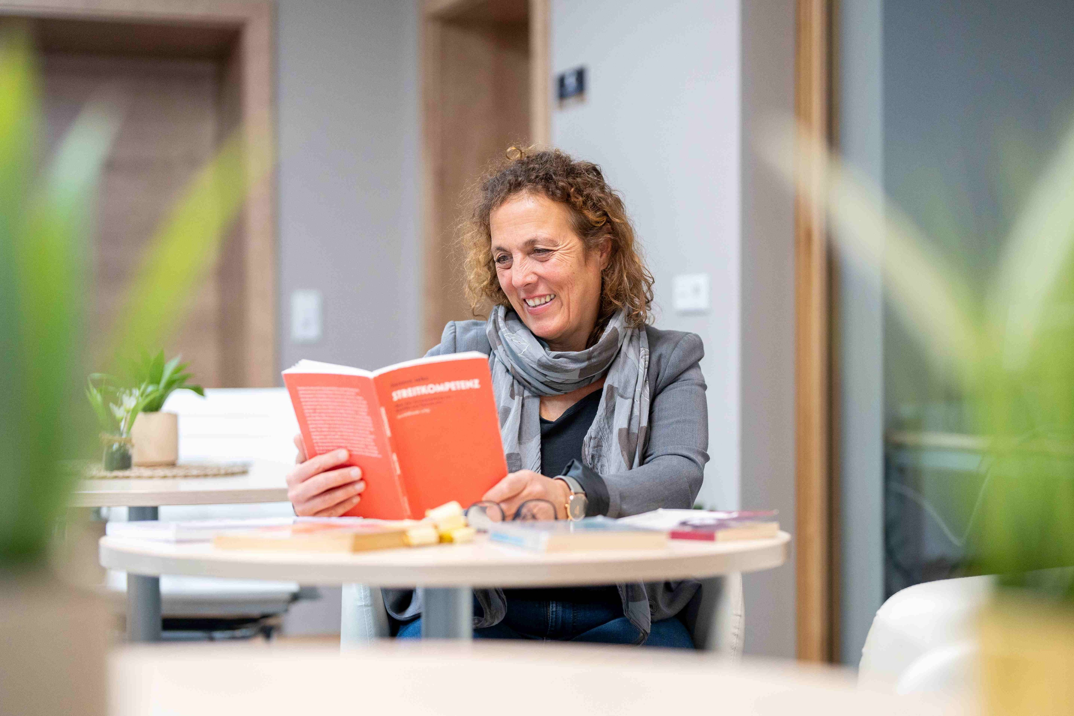 Birgit Seymann am Schreibtisch in ihrem Büro beim Lesen des Buches Streikompetenz von Susanne Jalka